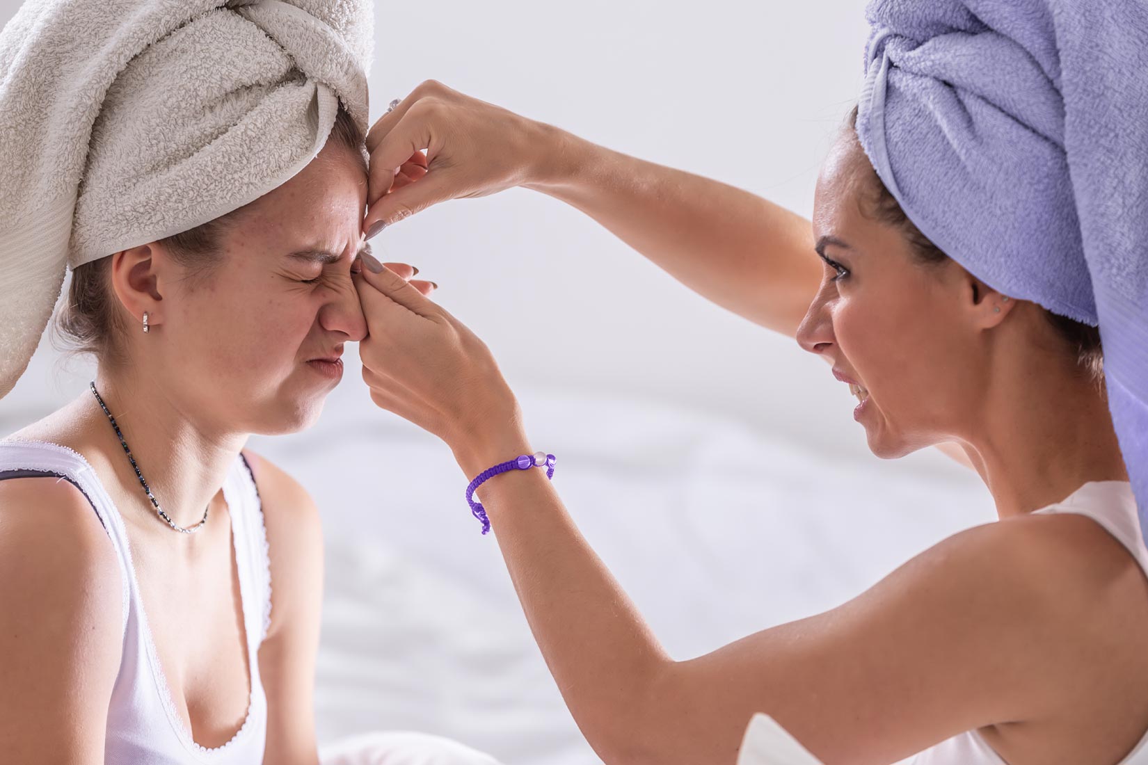Madre exprimiendo grano del rostro de su hija.